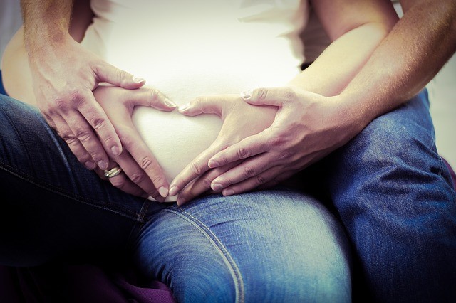 Men put hands on the pregnant wife's belly - Joy of Life Surrogacy