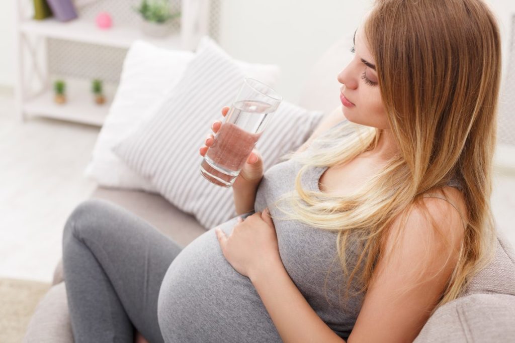 A Surrogate mother seating on sofa and drink a cup of water - Joy of Life Surrogacy